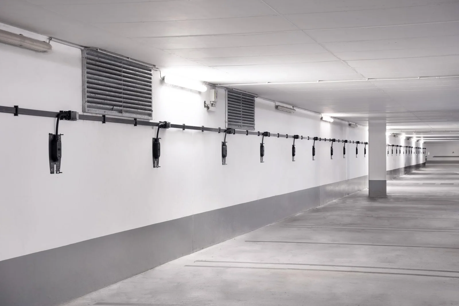 Vlakbandkabel met aftakkingen en voorbereide Zaptec Pro backplates in een parkeergarage